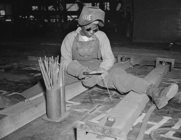 Black and white photograph of an African American woman using welding tools. 