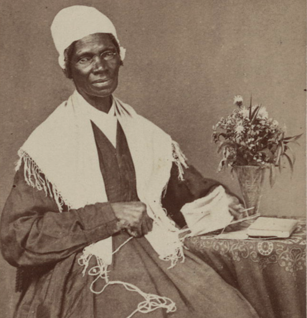 Photograph of Sojourner Truth wearing wire-rimmed spectacles, a dark, long-sleeved dress, and a rounded white cap. 