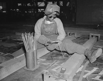 Black and white photograph of an African American woman using welding tools. 